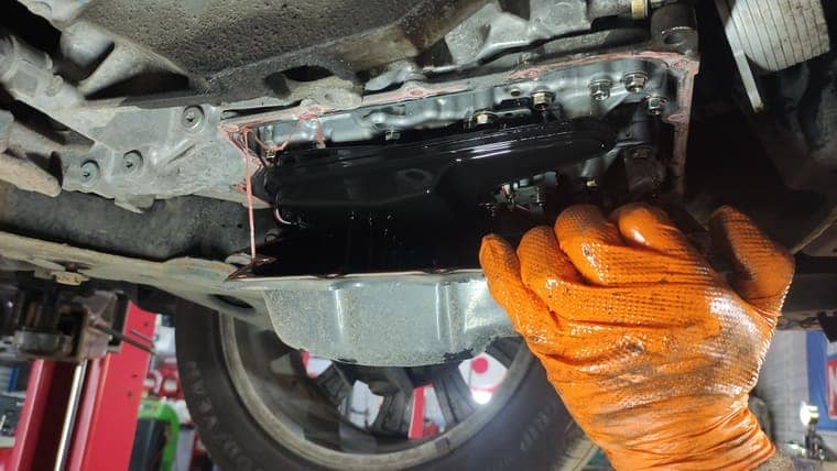 Аккуратно снимаем поддон коробки. В нем остается небольшое количество старого масла.