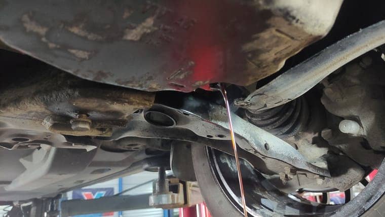 Заводим двигатель автомобиля. Переключаем передачи АКПП, задерживаясь на каждой 2–3 секунды. Переводим селектор в положение “P”. Откручиваем пробку на поддоне и излишки масла вытекают.