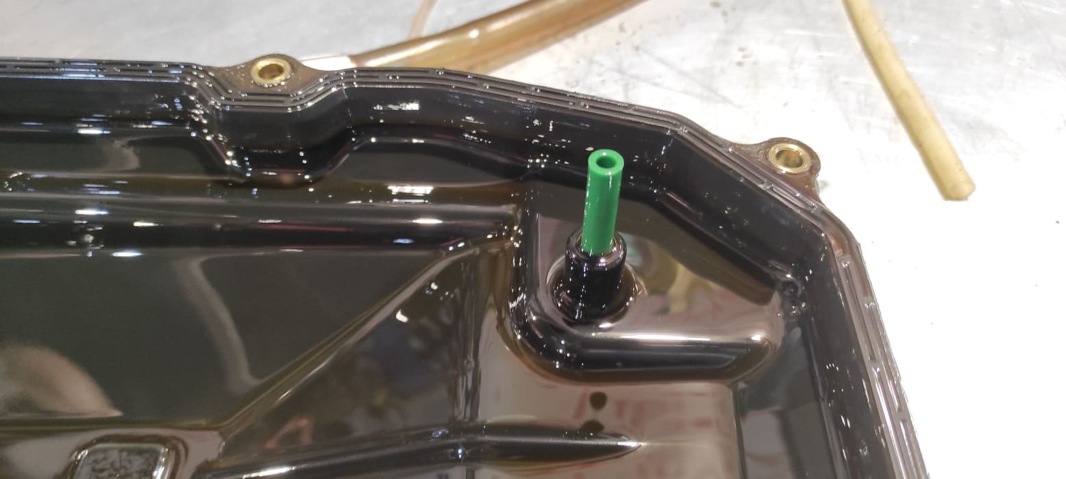 Вот эта зеленая трубка – переливная трубка. Она помогает регулировать уровень масла в коробке после замены. Излишки масла выльются из АКПП и останется только необходимое количество. Температура регулировки уровня масла 35 – 45 градусов.