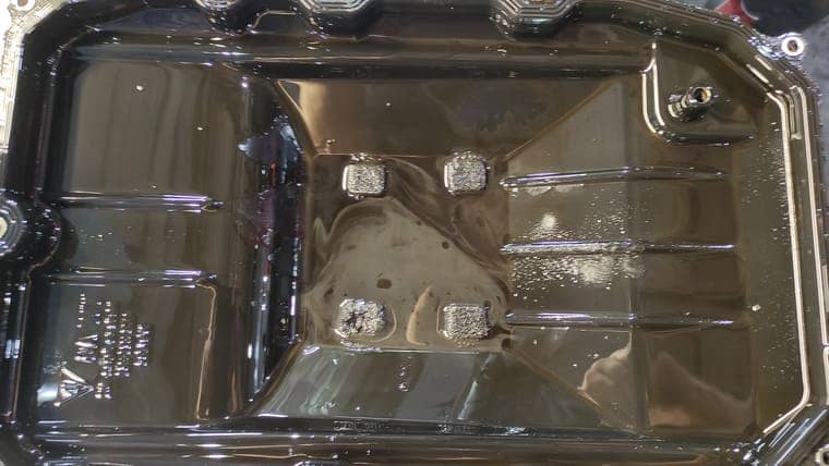 Осматриваем снятый поддон коробки. На магнитах присутствует металлическая пыль, на дне поддона скопился так называемый песок, жесткие частицы, продукты горения масла.