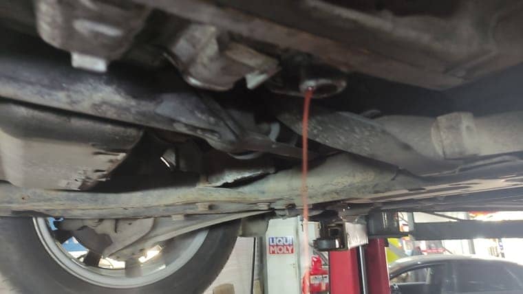 Запускаем двигатель автомобиля, переключаем передачи, задерживаясь на каждой на 2–3 секунды и откручиваем уровневую заглушку. Масло должно вытекать до отдельных капель.