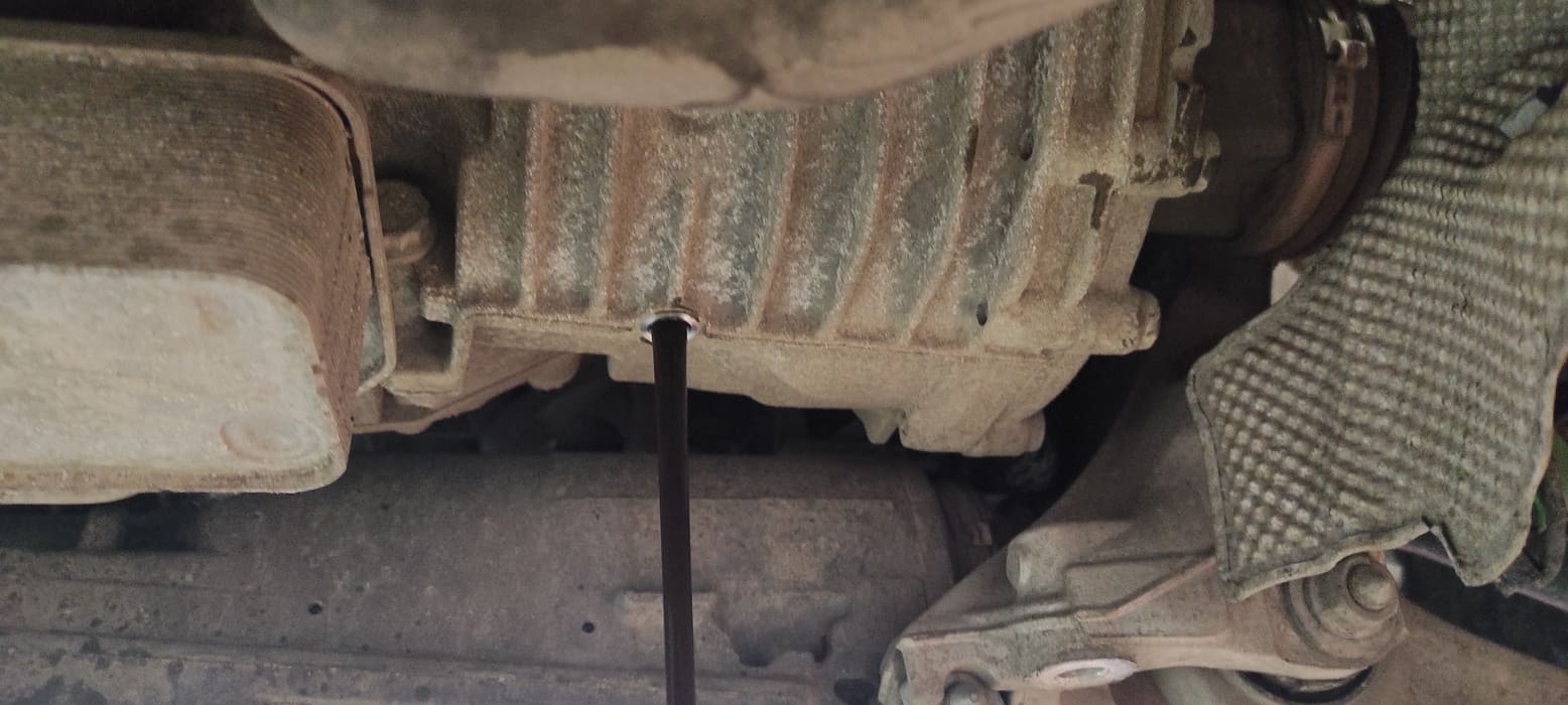 Переходим к переднему редуктору. Он расположен сбоку ближе к переднему правому колесу. Для удаления старого масла необходимо открутить сливную и заливную пробки. На этом фото видно сливное отверстие.