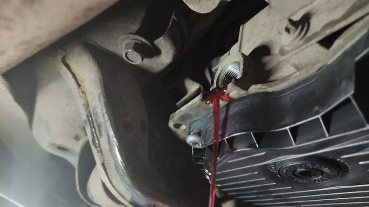 Заводим двигатель автомобиля, переключаем передачи, задерживаясь на каждой на 2–3 секунды. Откручиваем контрольную пробку. Масло вытекает до отдельных капель, значит, уровень масла верный.